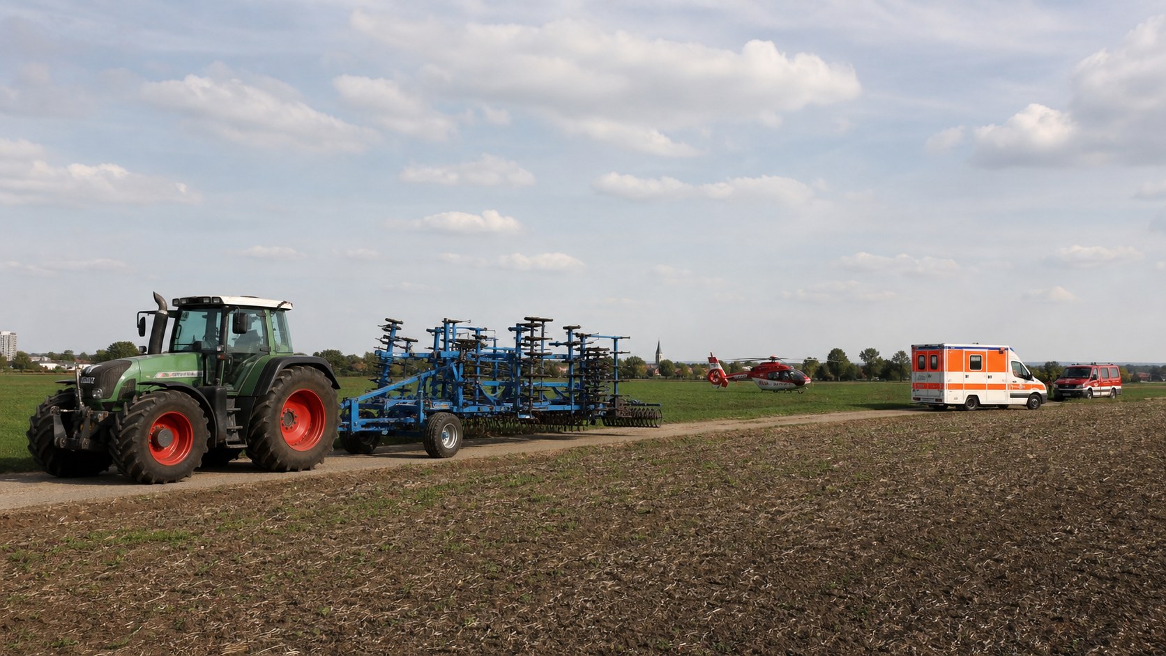 Traktor, landwirtschaftliches Gerät und Rettungskräfte auf einem Feld als redaktionelles Symbolbild