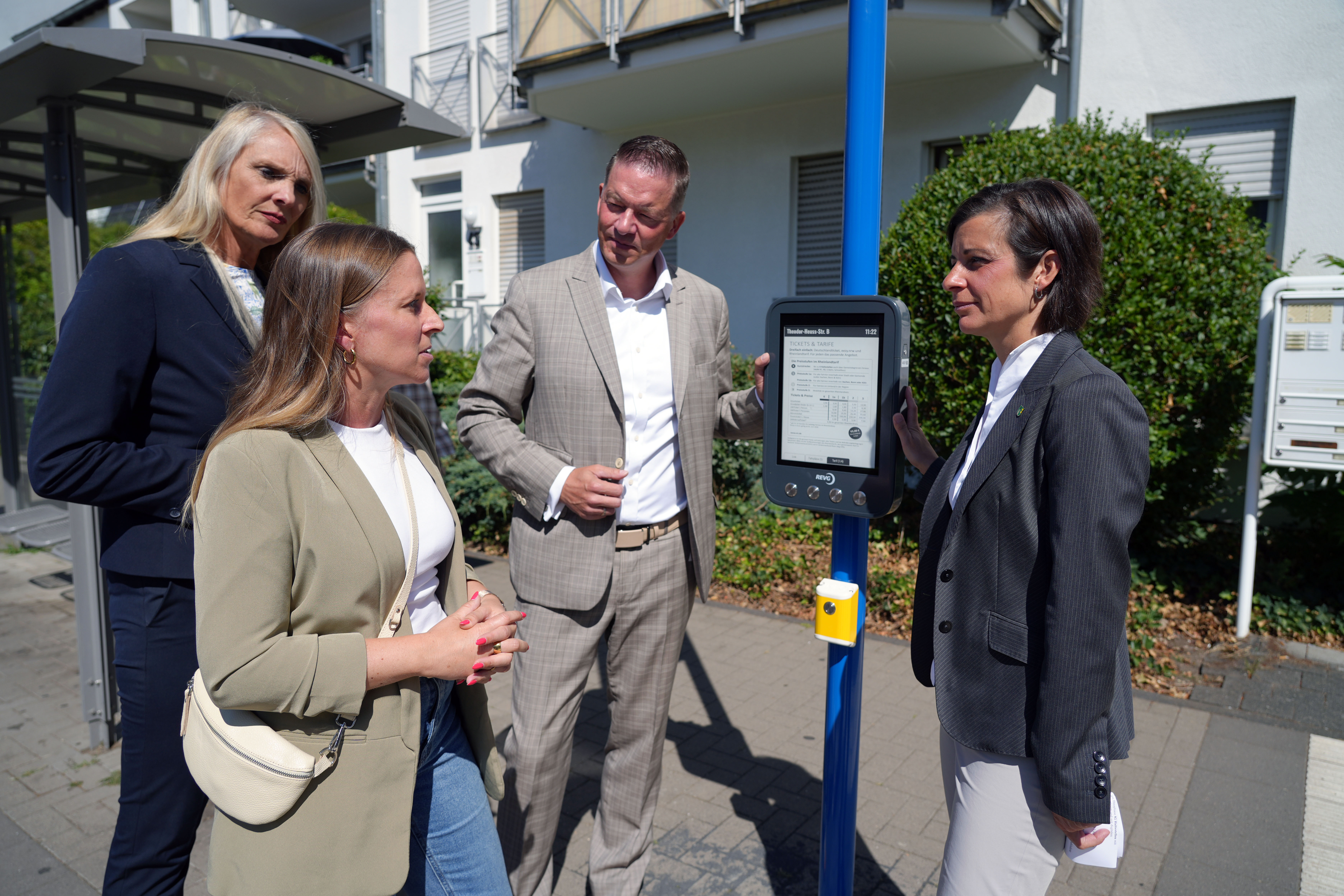 Vertreterinnen und Vertreter von Stadt und REVG an einer digitalen Fahrgastanzeige in Erftstadt